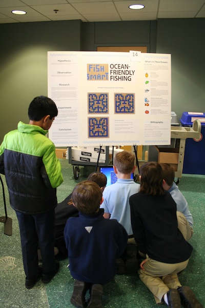 Students surround the one laptop at the science fair. 